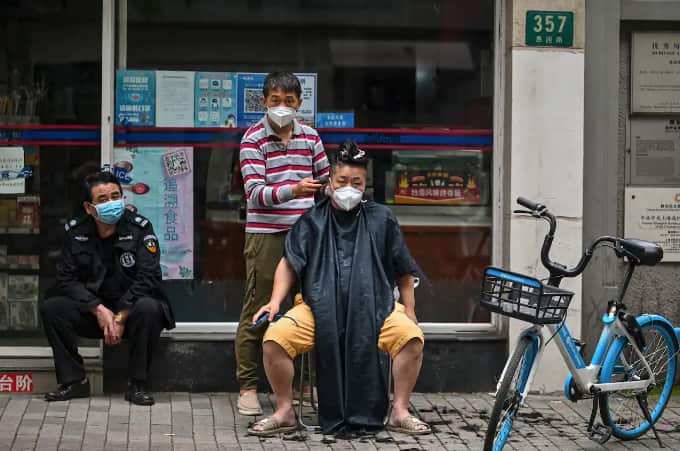 A man has a haircut on a street in the Jing'an district of Shanghai on 30 May 2022.