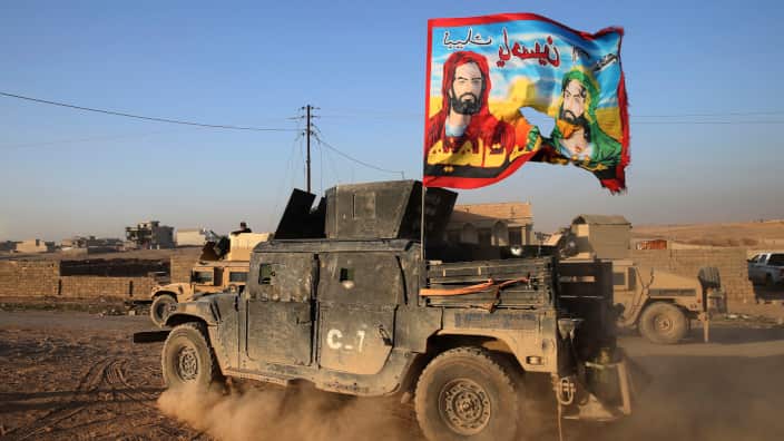 an Iraqi special forces humvee passes with a Shiite flag 