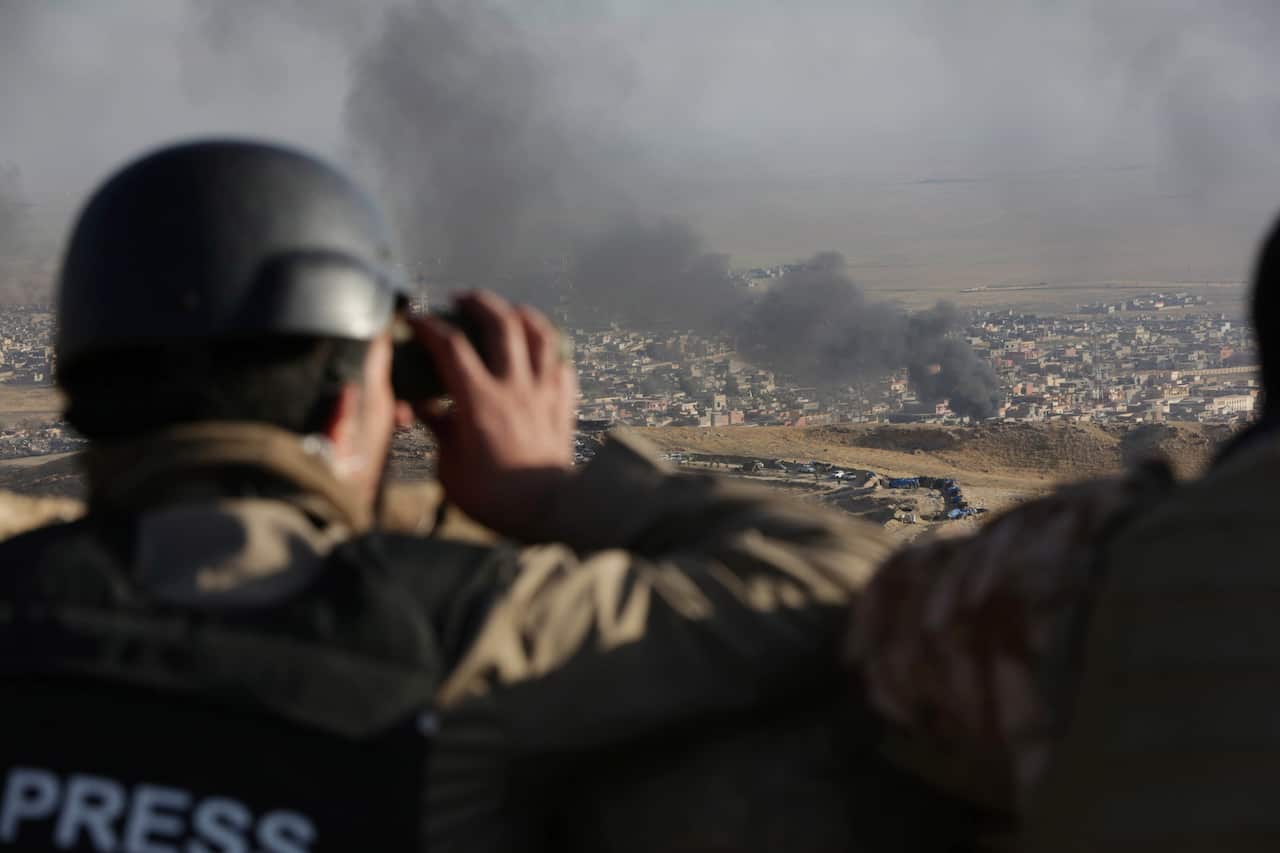 A journalist watches as smoke rises over Sinjar, northern Iraq from oil fires set by Islamic State militants.