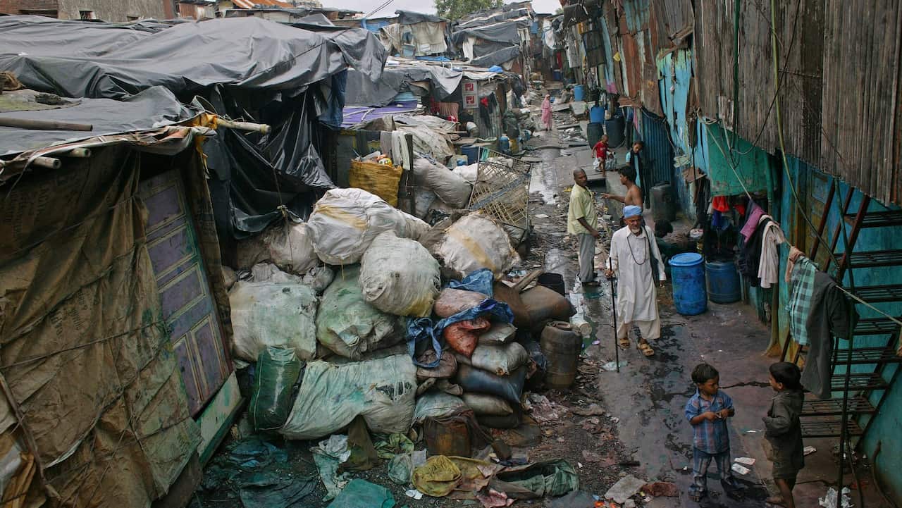 An old man strolls along a water pipe in Dharavi slums
