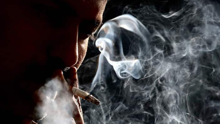 A shilloutted man smokes a cigarette