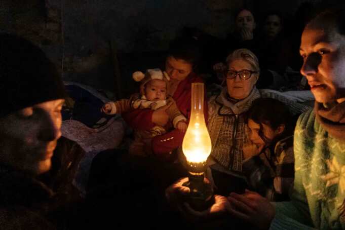 People sit around a lamp in a bomb shelter in Mariupol, Ukraine, on Sunday, 6 March, 2022.