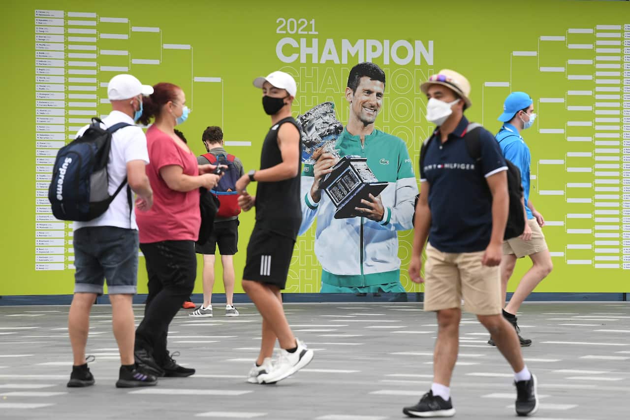 Spectators are seen walking past a picture of Novak Djokovic on Day 1 of the Australian Open Tennis Tournament at Melbourne Park, in Melbourne, Monday, January 17, 2022. (AAP Image/Dave Hunt) NO ARCHIVING