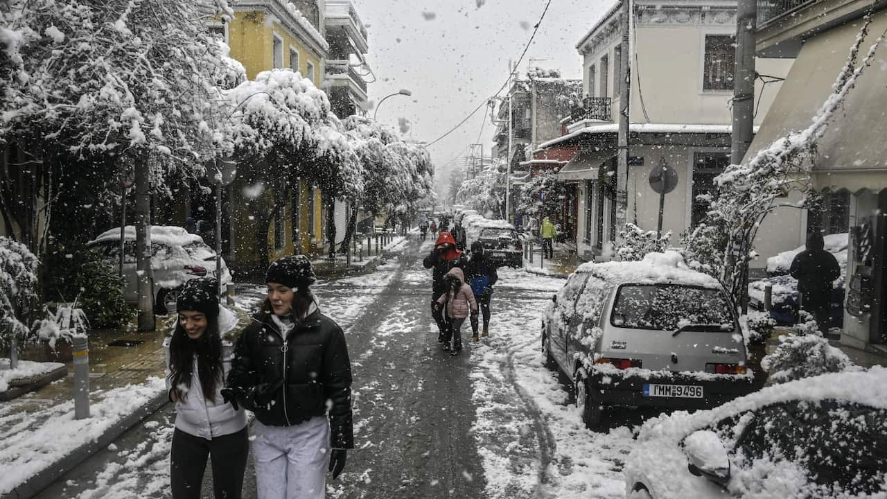 People walk under snow fall in Athens