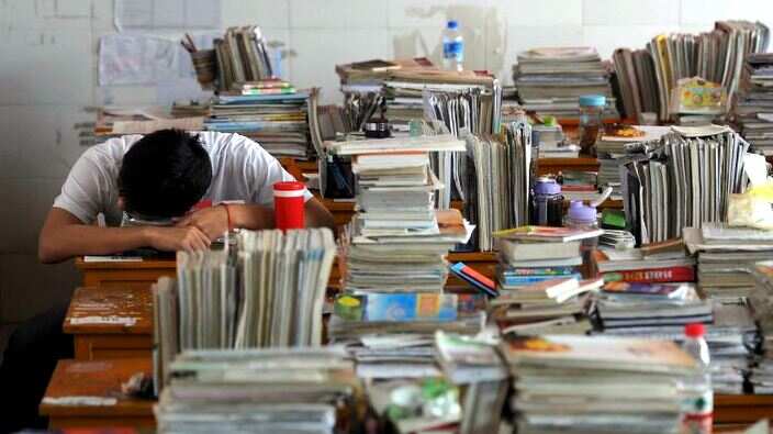 A student takes a nap on a desk during his lunch break in a classroom in Hefei