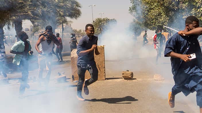 Demonstrators run from tear gas as they take part in a protest demanding the departure of Sudanese President Omar al-Bashir.