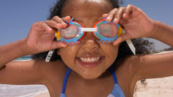 Smiling girl wearing goggles at beach