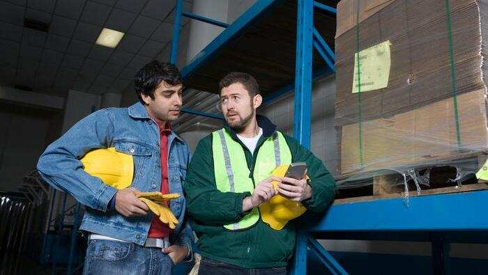 Men using calculator in factory