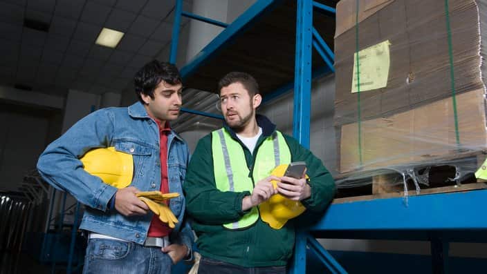Men using calculator in factory