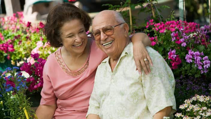 Senior Couple sitting among flowers at plant nursery portrait