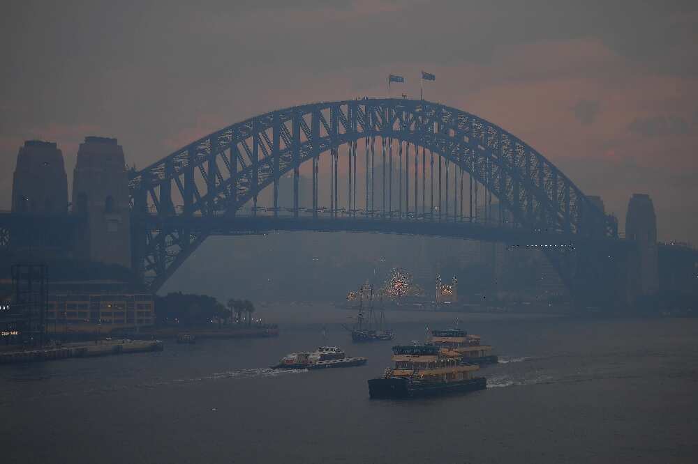 Commuter ferries sail past the Sydney Harbour Bridge as smoke haze from bushfires in New South Wales blankets the CBD.