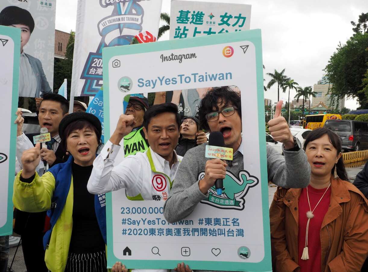 Taiwanese people holding frames reading 'Say Yes To Taiwan' and 'Call Us Taiwan at Tokyo Olympics,' urging people to vote in favor for the name change
