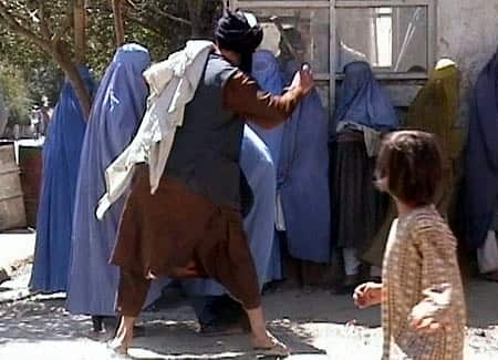 A member of the Taliban's religious police beating an Afghan woman in Kabul on August 26, 2001.