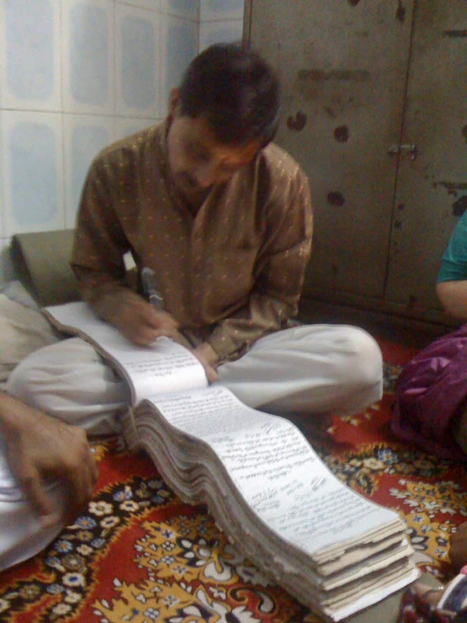 The priest at his gaddhi, making entries after Pooran's ashes were immersed in the holy Ganga
