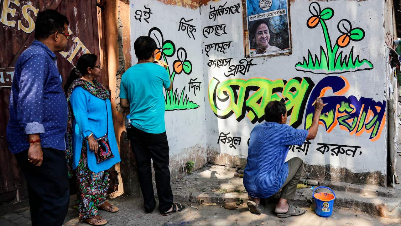 Supporters of Trinamool Congress party paint the party symbol on a wall ahead of the upcoming elections in West Bengal state in Kolkata, India, March 6, 2021.