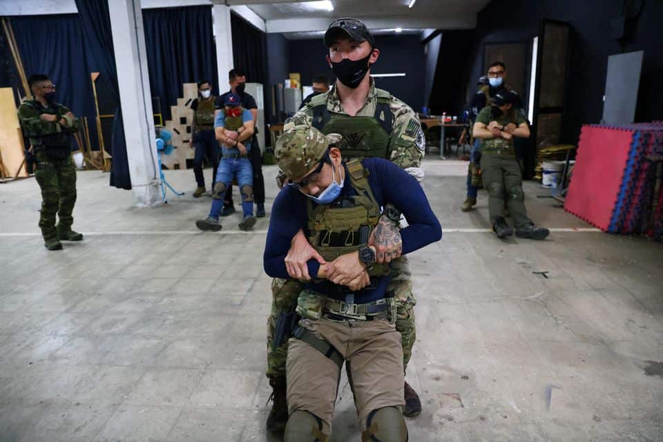 Personal trainer, Chris Chen, and other trainees practice carrying an injured person during an airsoft gun shooting lesson