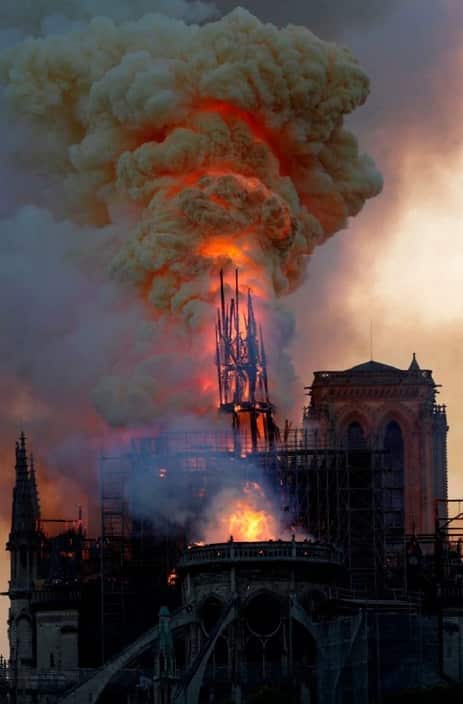 The steeple engulfed in flames collapses as the roof of the Notre-Dame de Paris Cathedral burns.
