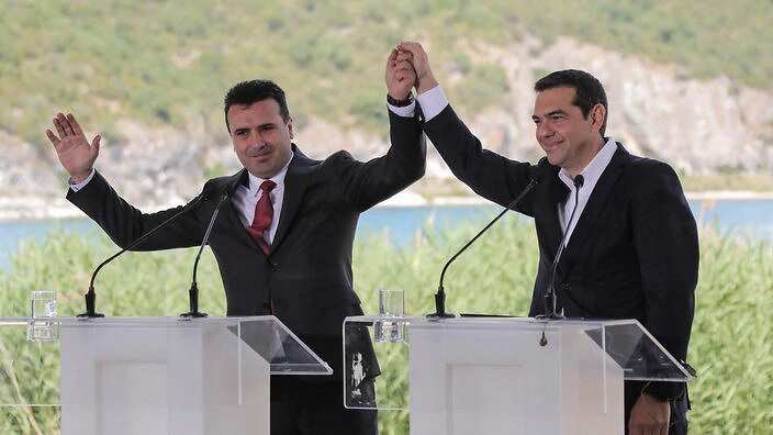 Greek Prime Minister Alexis Tsipras, right and his FYROM counterpart Zoran Zaev, raise their hands during the signing of the Prespa Agreement. 