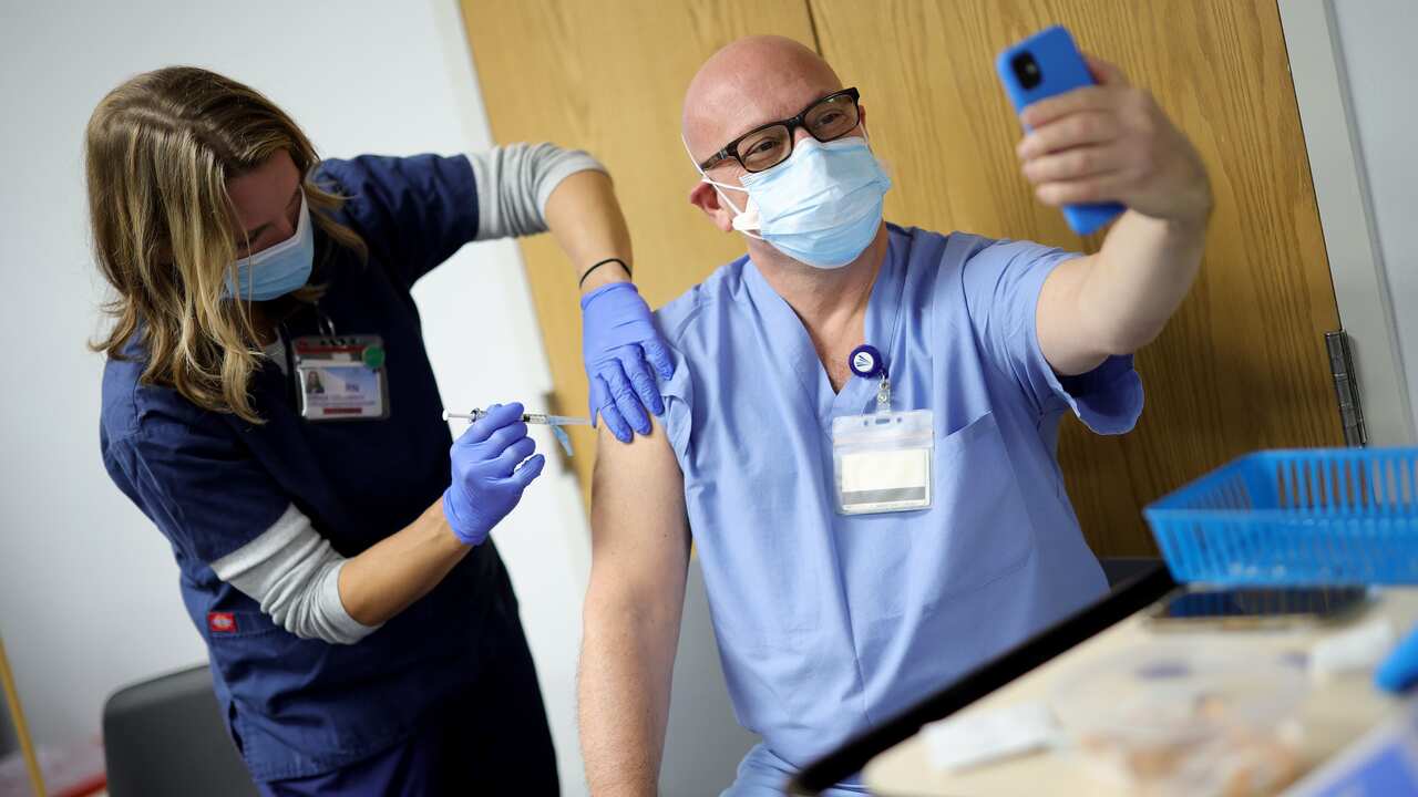 frontline medical worker, takes a selfie while he receives the vaccine for COVID-19 