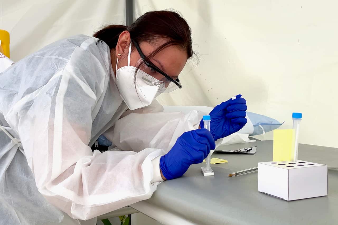 เจ้าหน้าที่กำลังหยดน้ำยาลงบนแผ่นตรวจเชื้อโควิดแบบทราบผลเร็ว