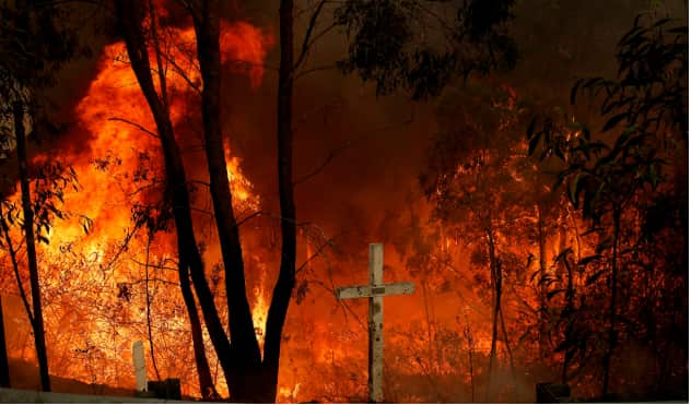 The Hillville bushfire burns out of control behind a memorial cross on the Pacific Highway at Possum brush south of Taree in the Mid North Coast region of NSW. AAP