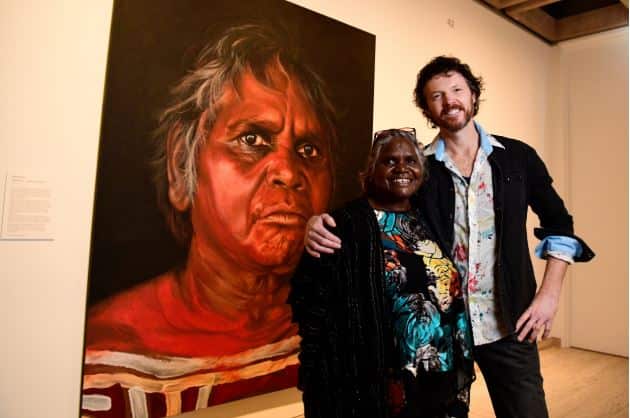 Aboriginal Elder Daisy Tjuparntarri Ward and artist David Darcy pose for a photograph in front of David's portrait of Daisy at the Art Gallery of NSW