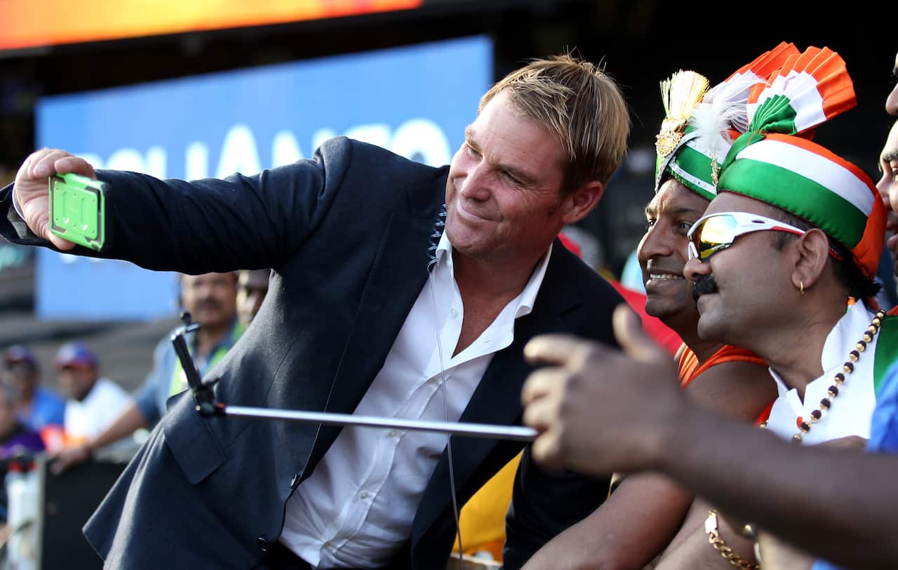 Former Australian cricketer Shane Warne takes a "selfie" photograph with Indian supporters during their Cricket World Cup semifinal between India and Australia in Sydney, Australia, Thursday, March 26, 2015. (AP Photo/Rob Griffith)