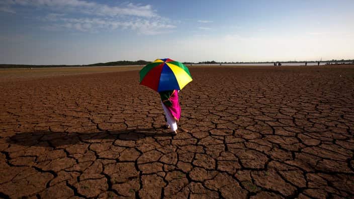 Girl holding umbrella in desert