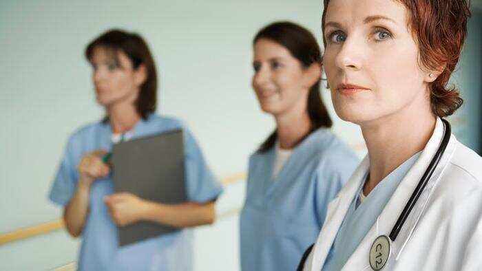 Serious Physician with Nurses in hospital corridor focus on physician portrait