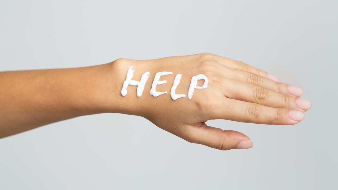 Word help written with cream on female hand