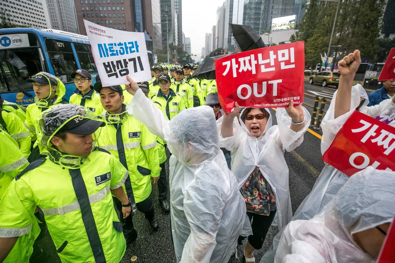 Anti-refugee activists chant slogans as they hold signs that read, 'Fake Refugees Out,' as they march next to the police on September 16, 2018 in Seoul