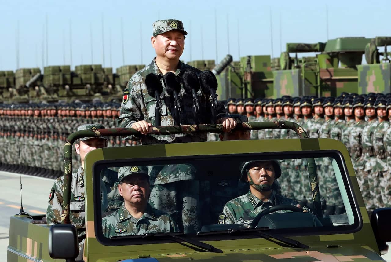 In this photo released by Xinhua News Agency, Chinese President Xi Jinping stands on a military jeep as he inspects troops in July 2017