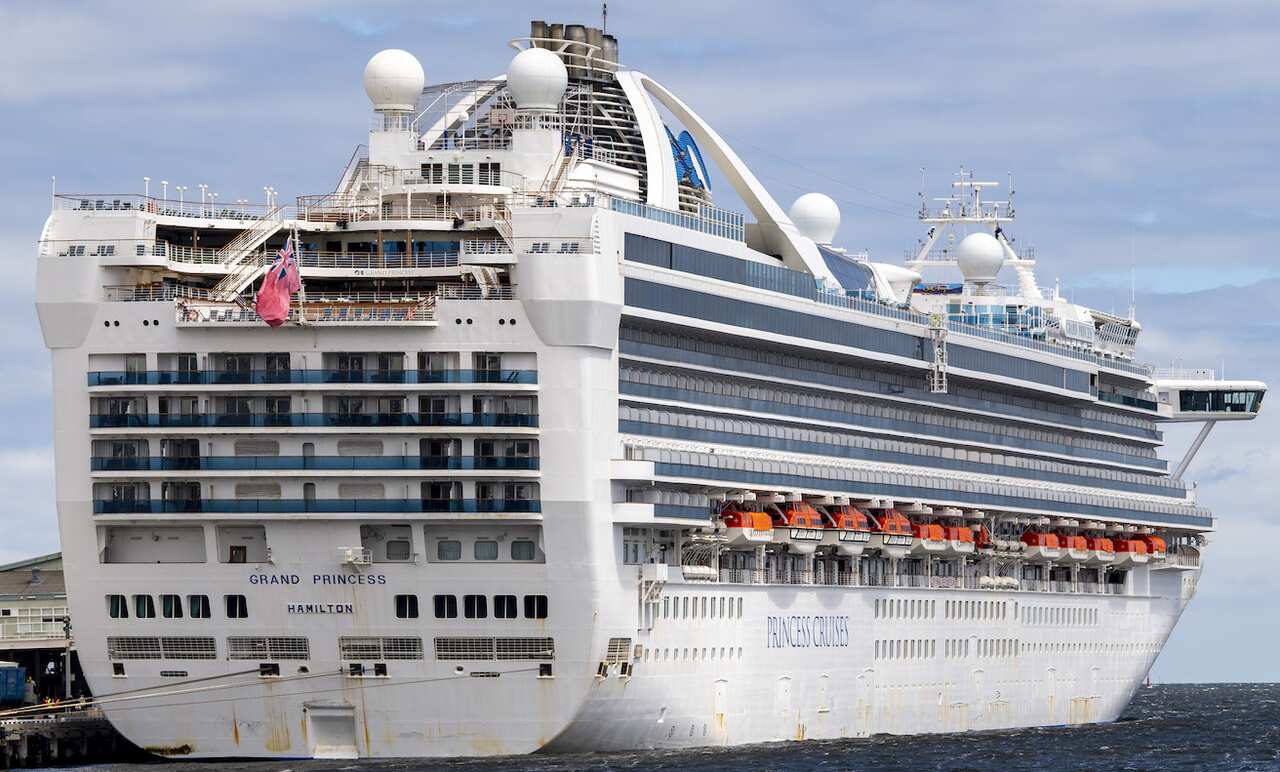 A large white cruise ship docked in the ocean.