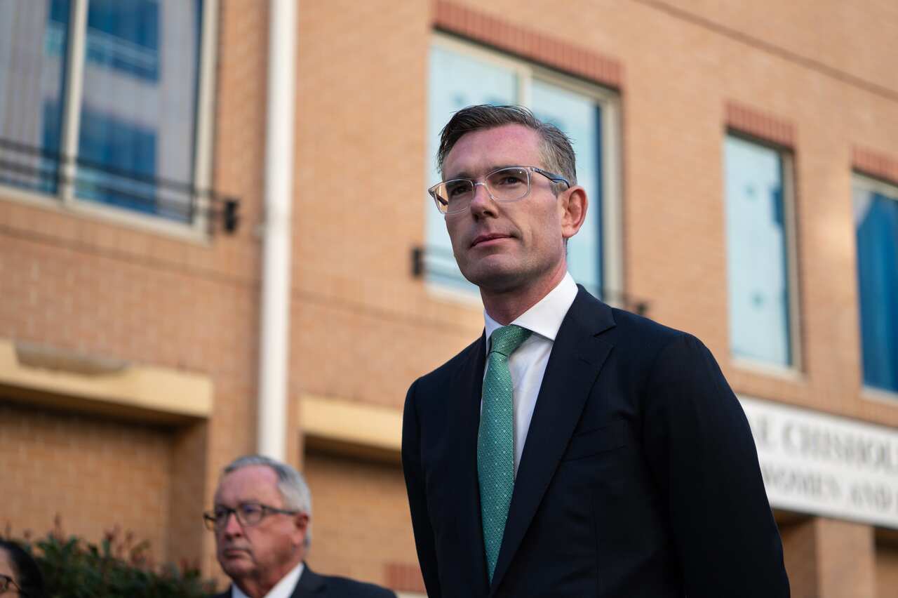 Dominic Perrottet in a suit, looking up. In the background is health minister Brad Hazzard. 
