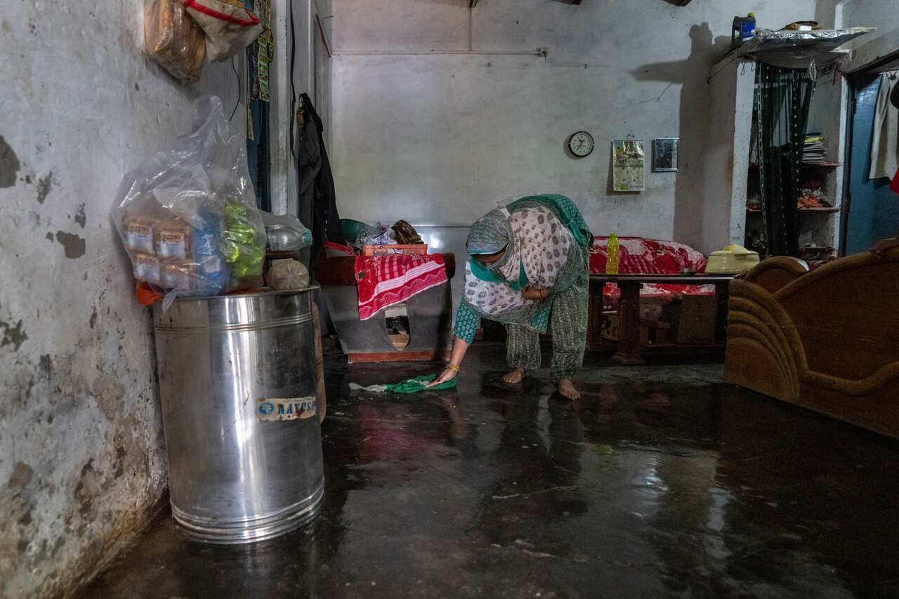 A woman mopping the floor of her flooded house.