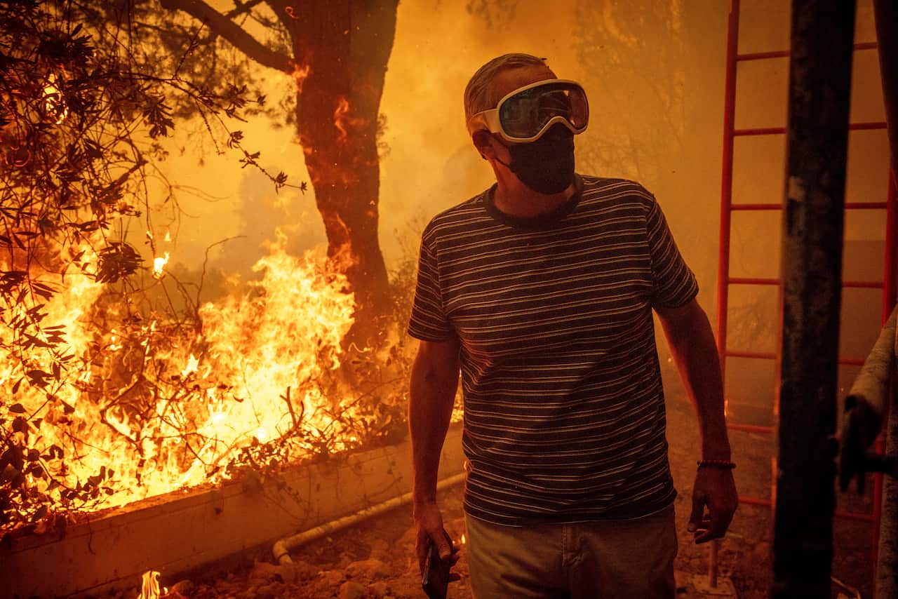 A man wearing goggles and a facemask next to a fire.