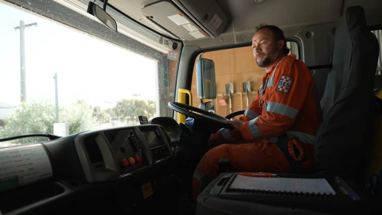 Hussaini driving in the SES truck wearing an orange SES uniform.
