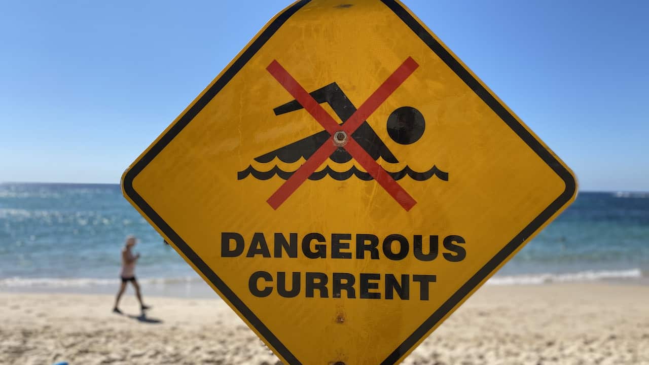 A safety sign reading 'dangerous current' pictured on beach