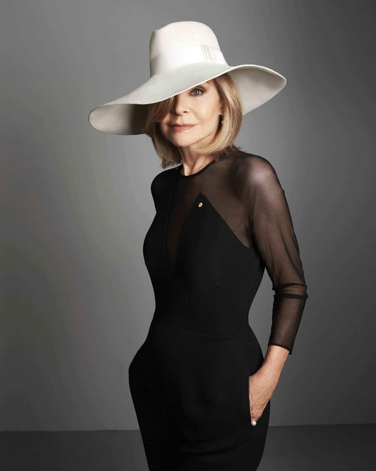 Carla Zampatti poses for a photograph in a large white hat.