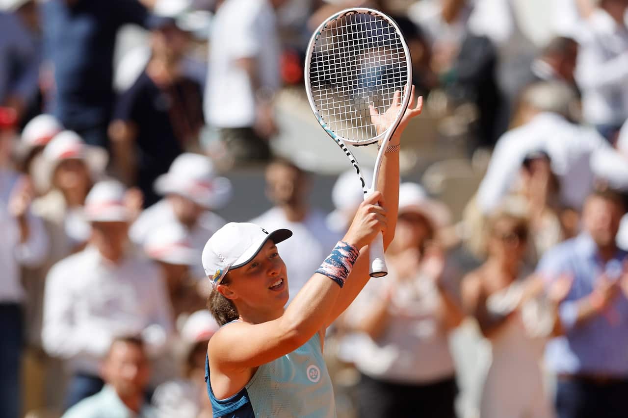 A tennis player holds her racquet in the air