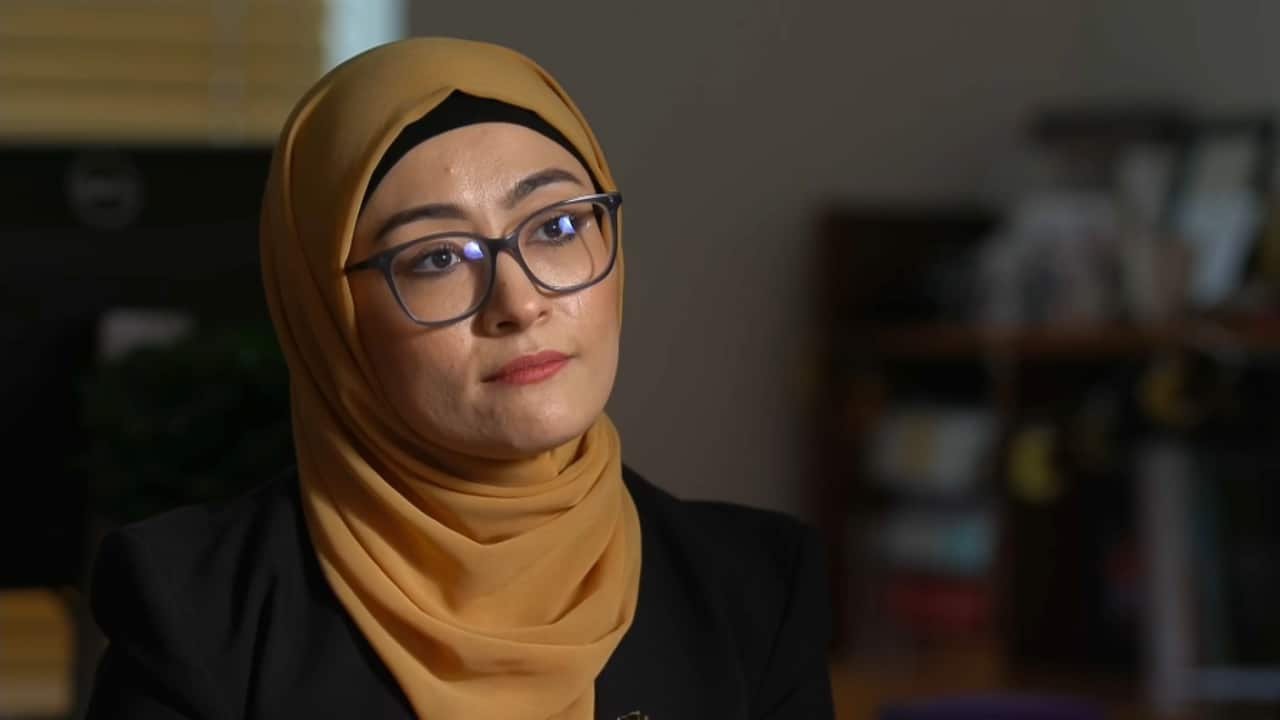 A woman wearing a hijab and glasses.