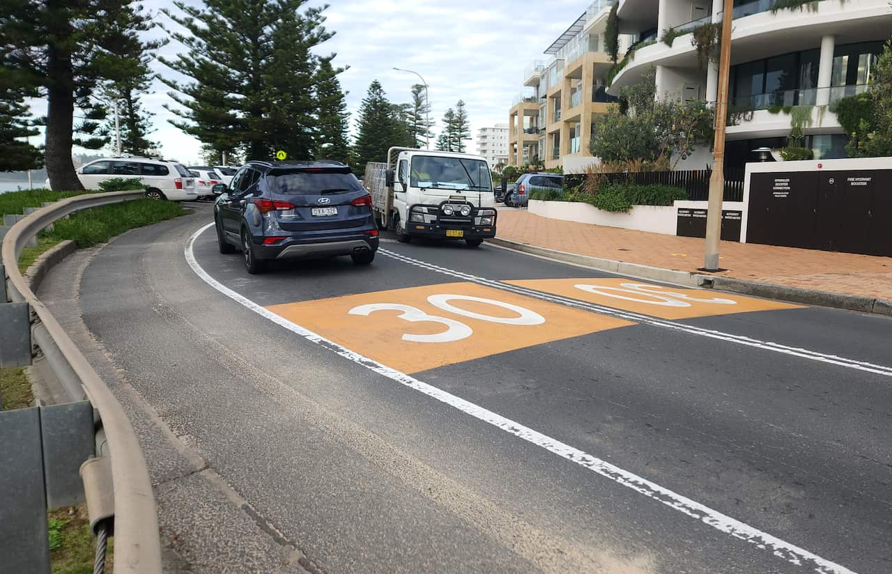 Two cars drive past one another on a road.