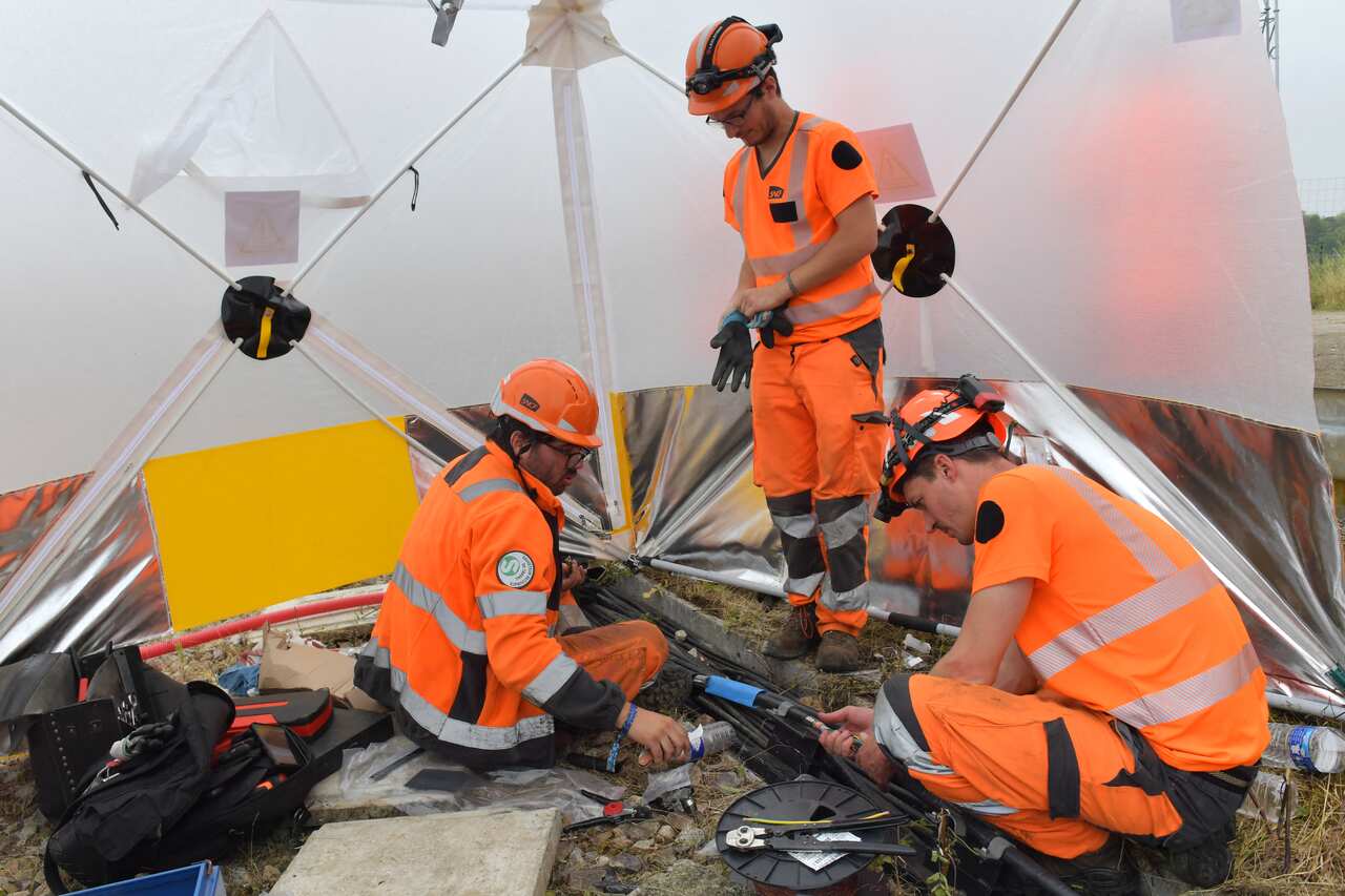 Workers operate to reconnect a signal box to a track.