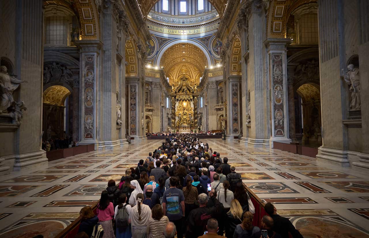 People line up in the centre of a basilica.