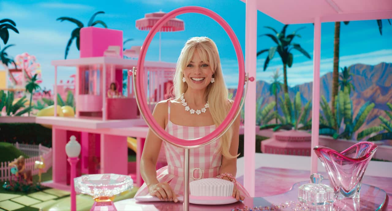 Margot Robbie as Barbie, dressed in pink in her dreamhouse