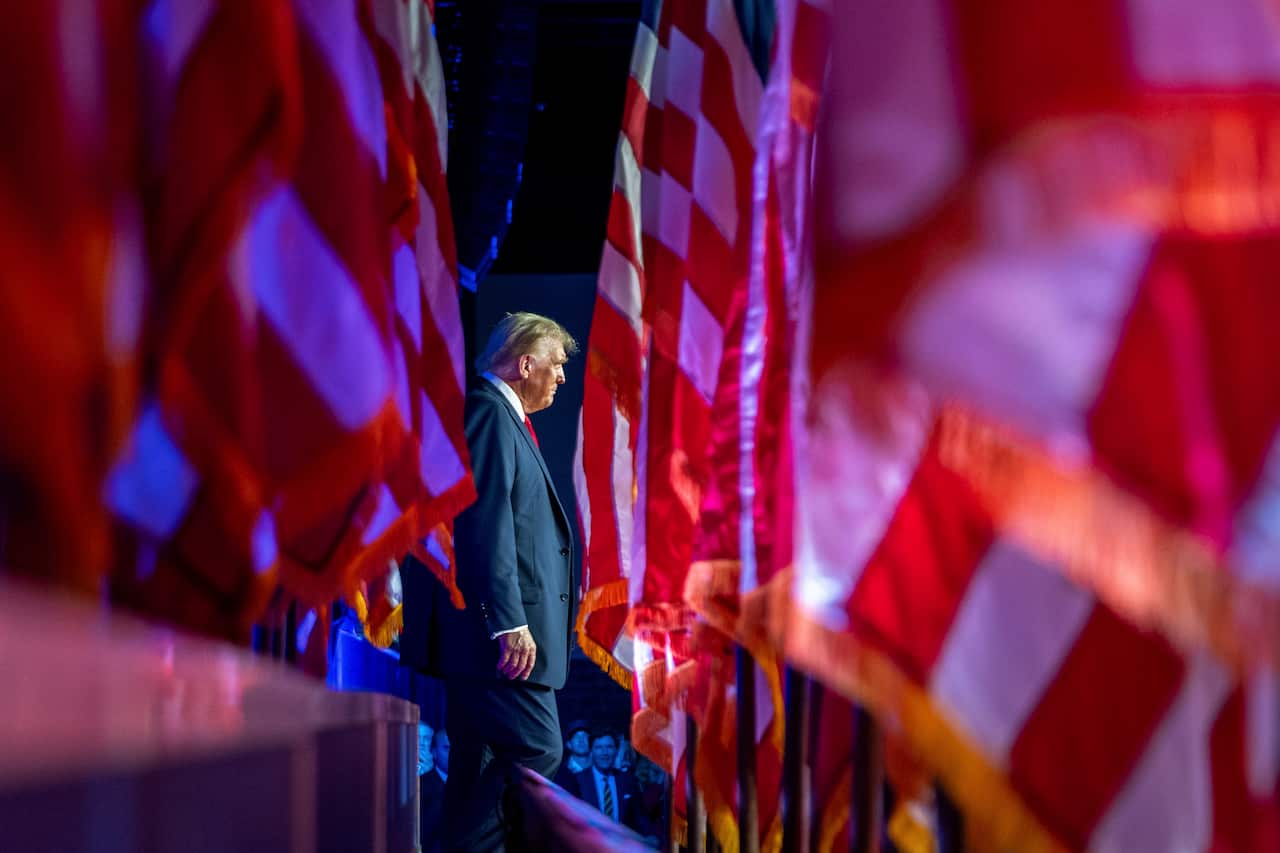 A side profile of Donald Trump as he walks past a row of flags. 