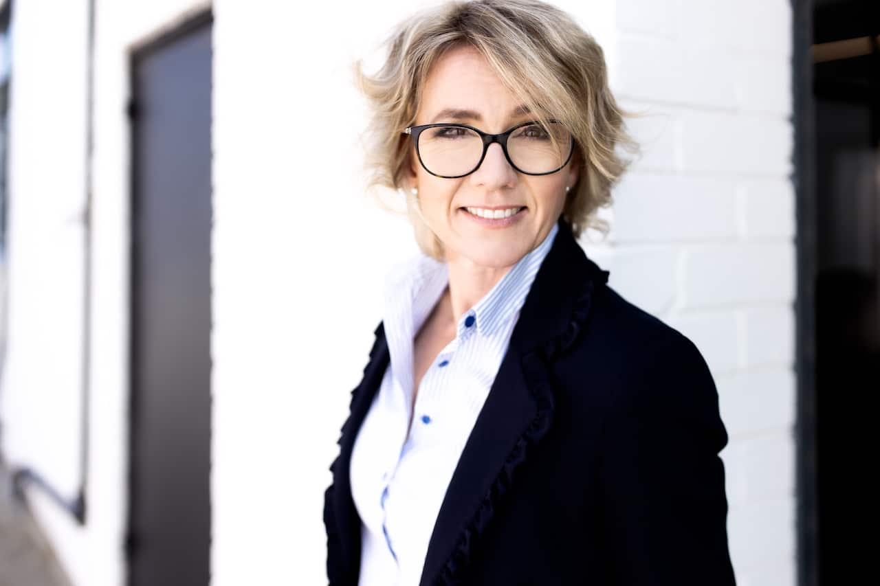 Kate in a suit, smiling at the camera. 