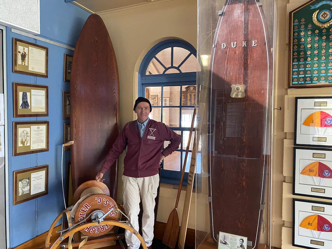 Freshwater Surf Lifesaving Club Historical Committee Member, Eric Middledorp, stands with Duke Kahanamoku's surfboard. The board was used at Freshwater Beach in the summer of 1914/15 during Duke's surfing exhibition. 