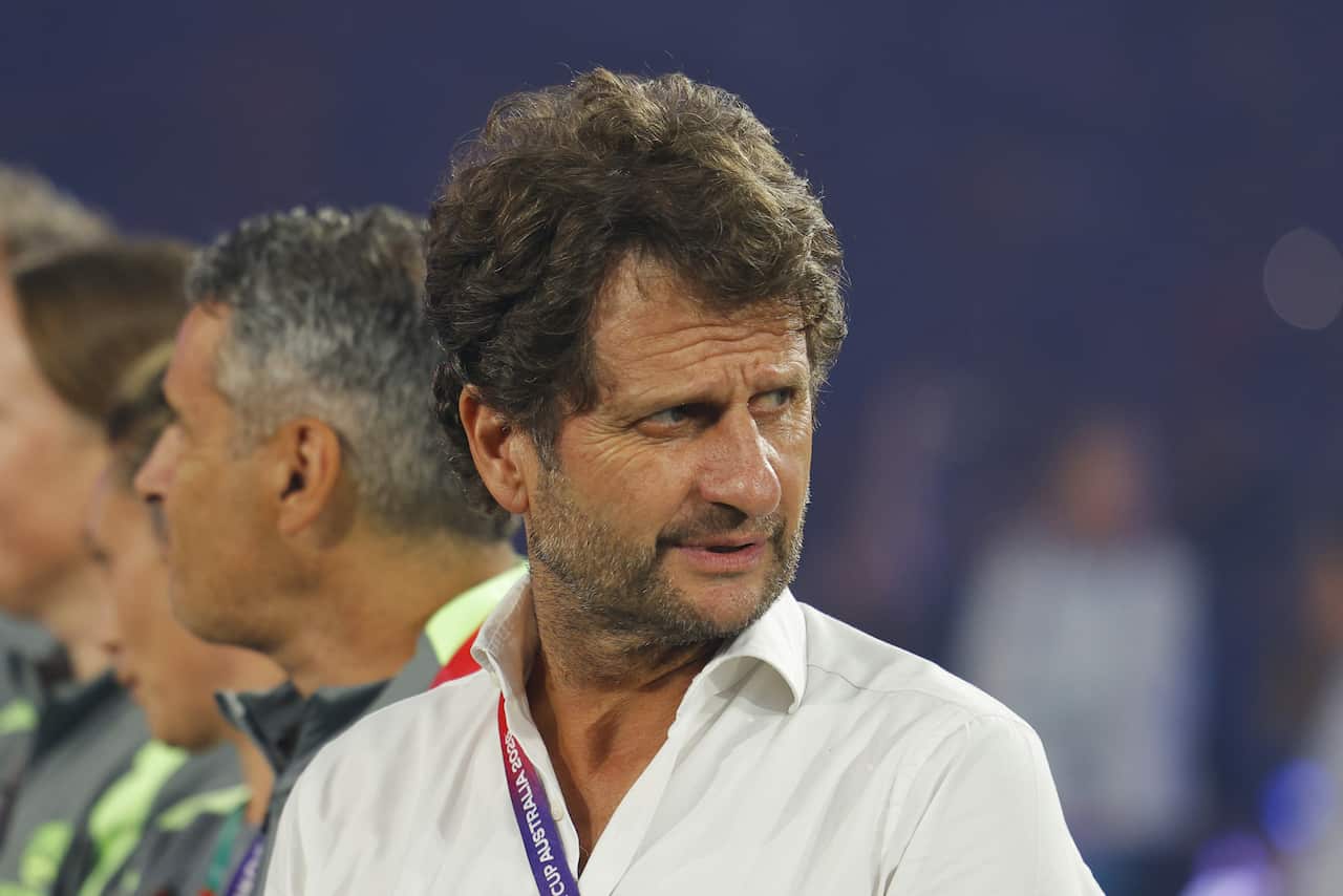 A medium close up image of Matildas manager Joe Montemurro. The image was taken during the 2026 Women's Asian Cup final in Sydney. He wears a white button down shirt over which he has slung a purple lanyard.