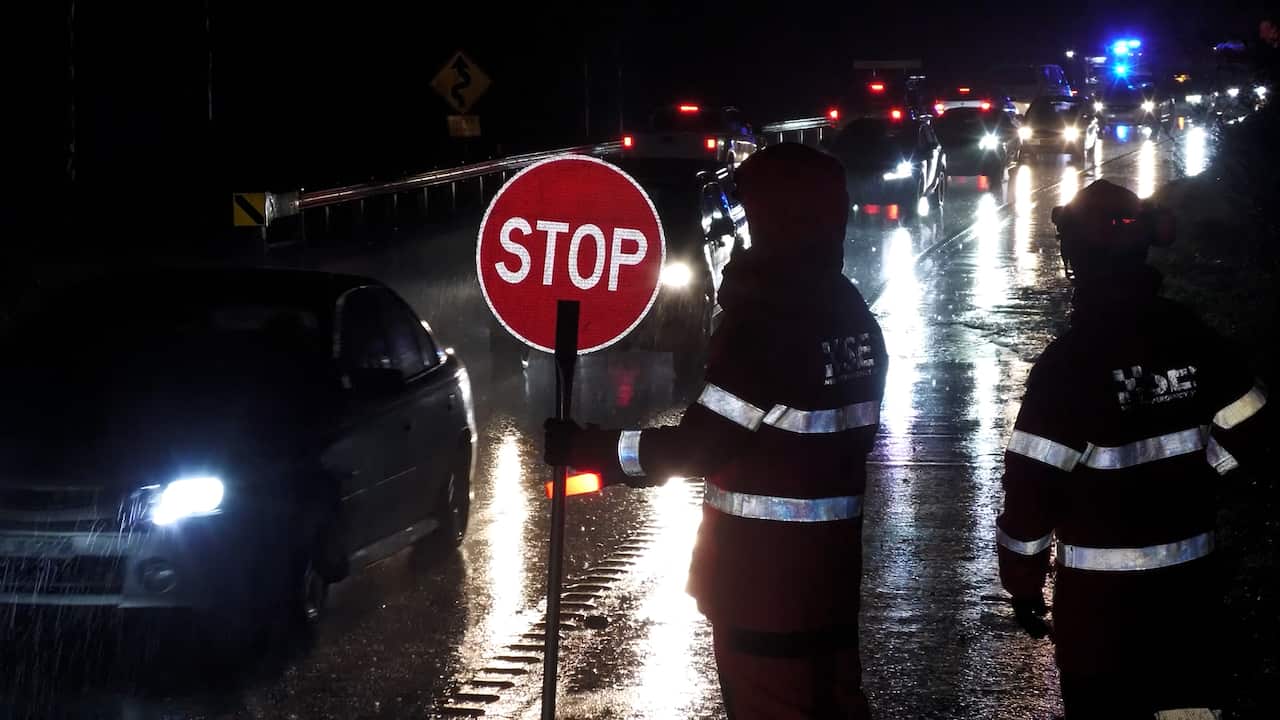 Rescue workers direct traffic at night wearing reflective clothing.